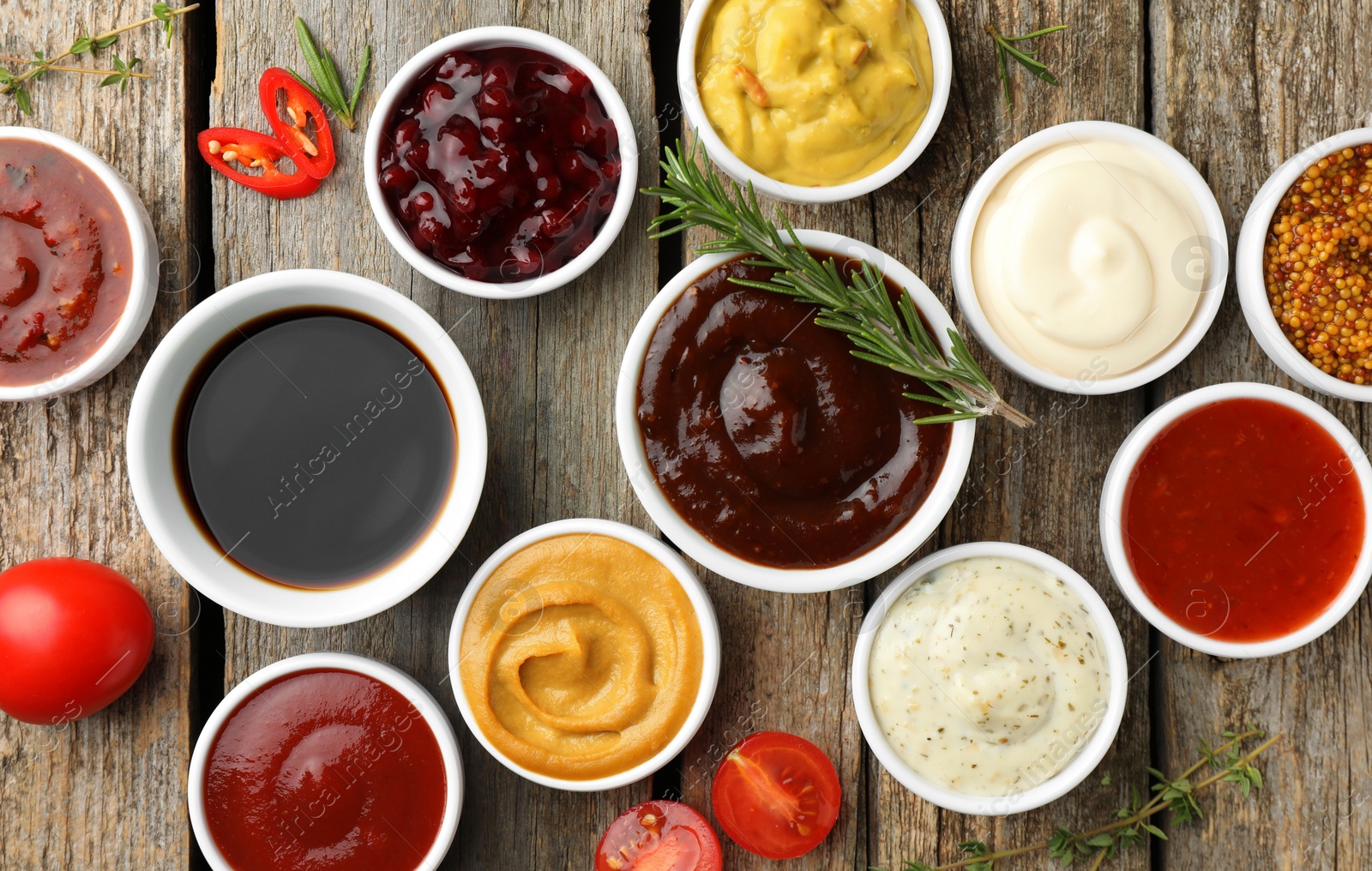 Photo of Different tasty sauces in bowls and ingredients on wooden table, flat lay