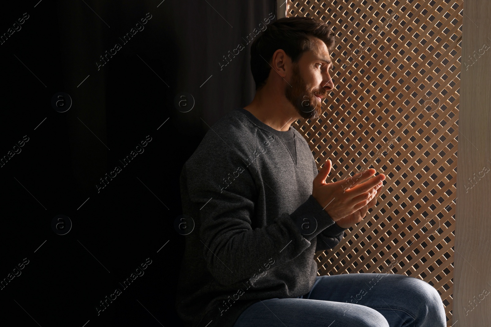 Photo of Man listening to priest during confession in booth, space for text