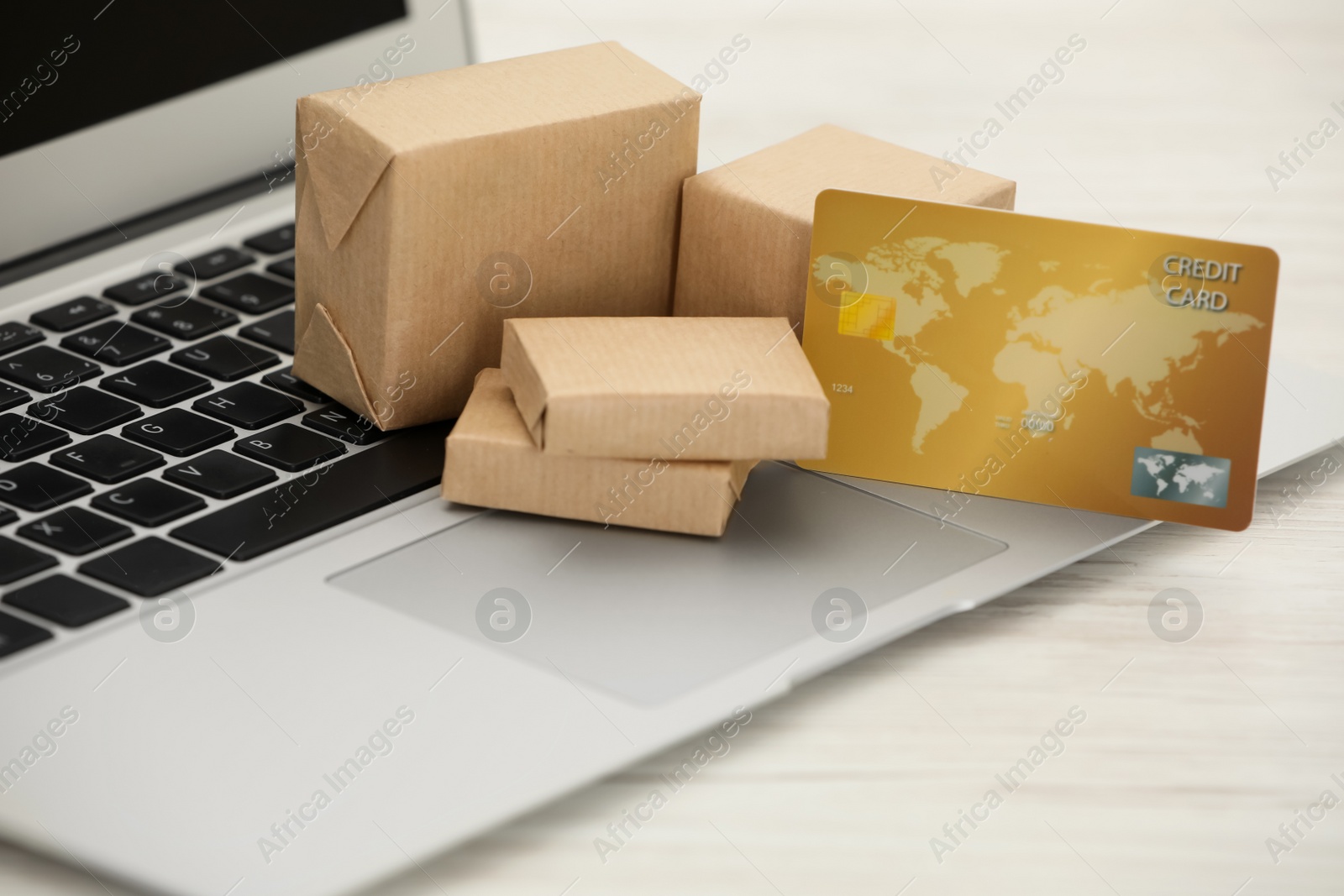 Photo of Online payment concept. Bank card and small boxes with laptop on white wooden table