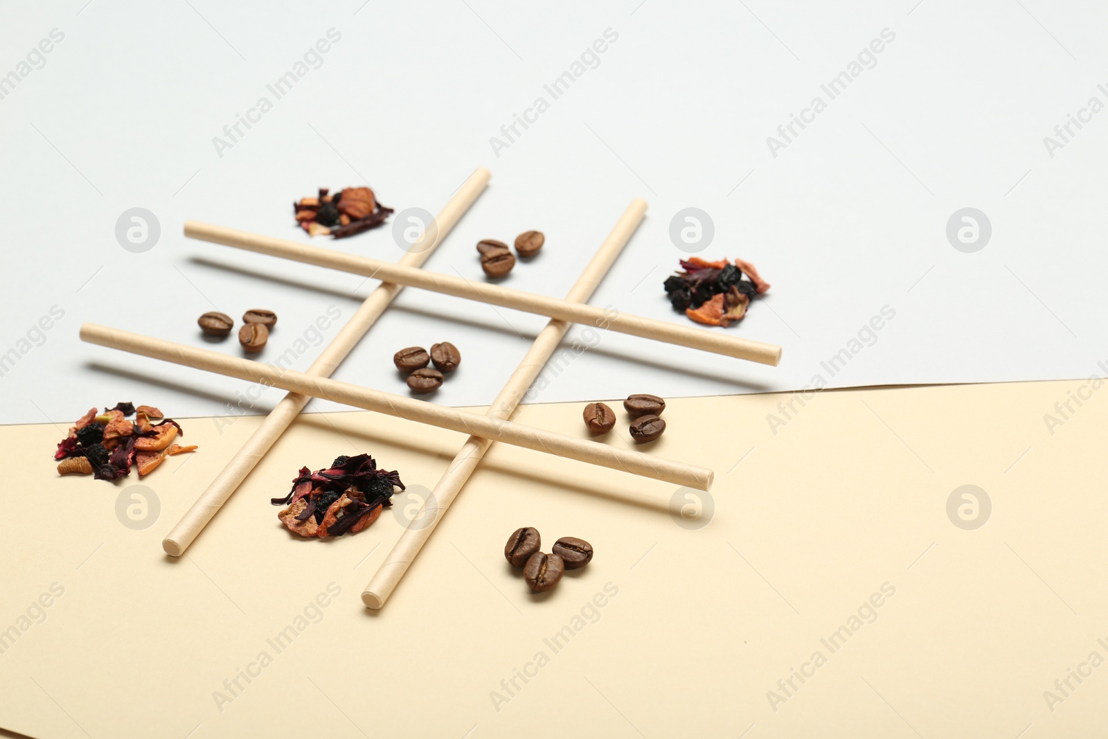 Photo of Tic tac toe game made with coffee beans and dry tea leaves on color background
