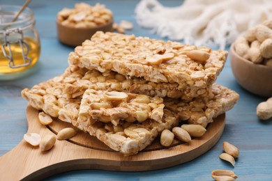 Photo of Delicious peanut bars (kozinaki) and ingredients on light blue wooden table