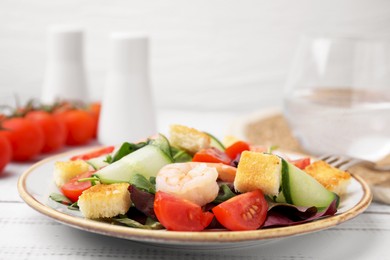 Photo of Tasty salad with croutons, tomato and shrimps on white wooden table, closeup