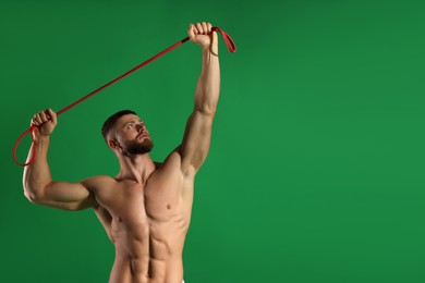 Photo of Muscular man exercising with elastic resistance band on green background. Space for text