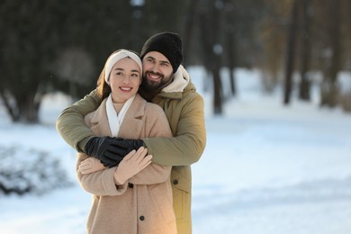 Beautiful young couple enjoying winter day outdoors. Space for text