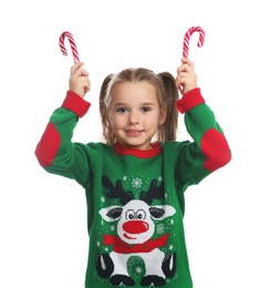 Photo of Cute little girl in Christmas sweater holding candy canes on white background