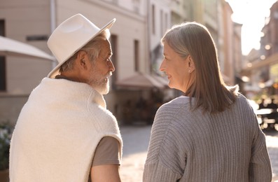 Photo of Affectionate senior couple walking outdoors, back view