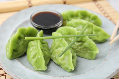 Delicious green dumplings (gyozas) and soy sauce on plate, closeup