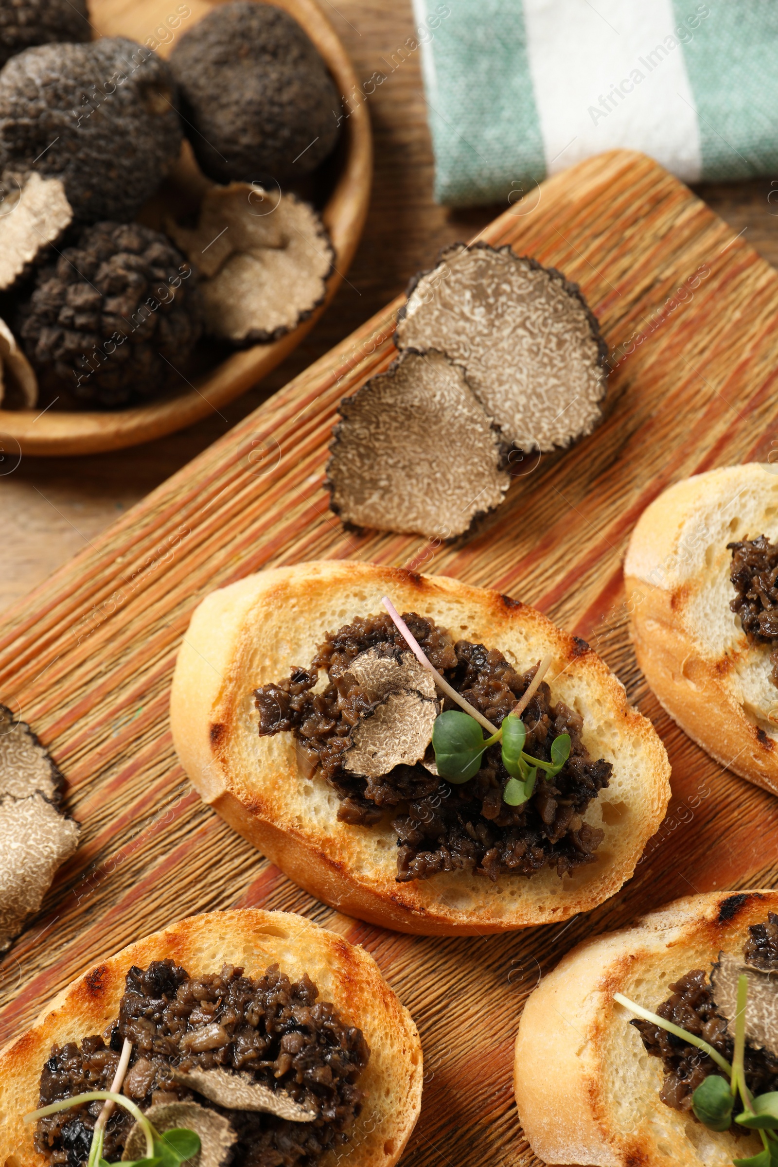 Photo of Delicious bruschettas with truffle sauce and microgreens on wooden table