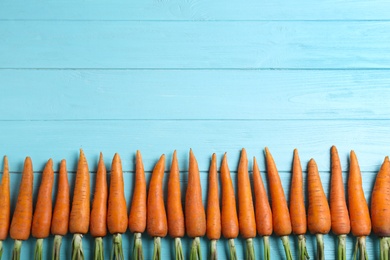 Photo of Ripe carrots on light blue wooden table, flat lay. Space for text