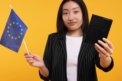 Photo of Immigration to European Union. Woman with passport and flag on orange background, selective focus