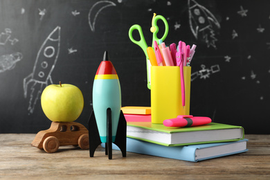 Bright toy rocket, car and school supplies on wooden table