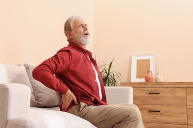 Photo of Senior man suffering from pain in his back at home. Arthritis symptoms