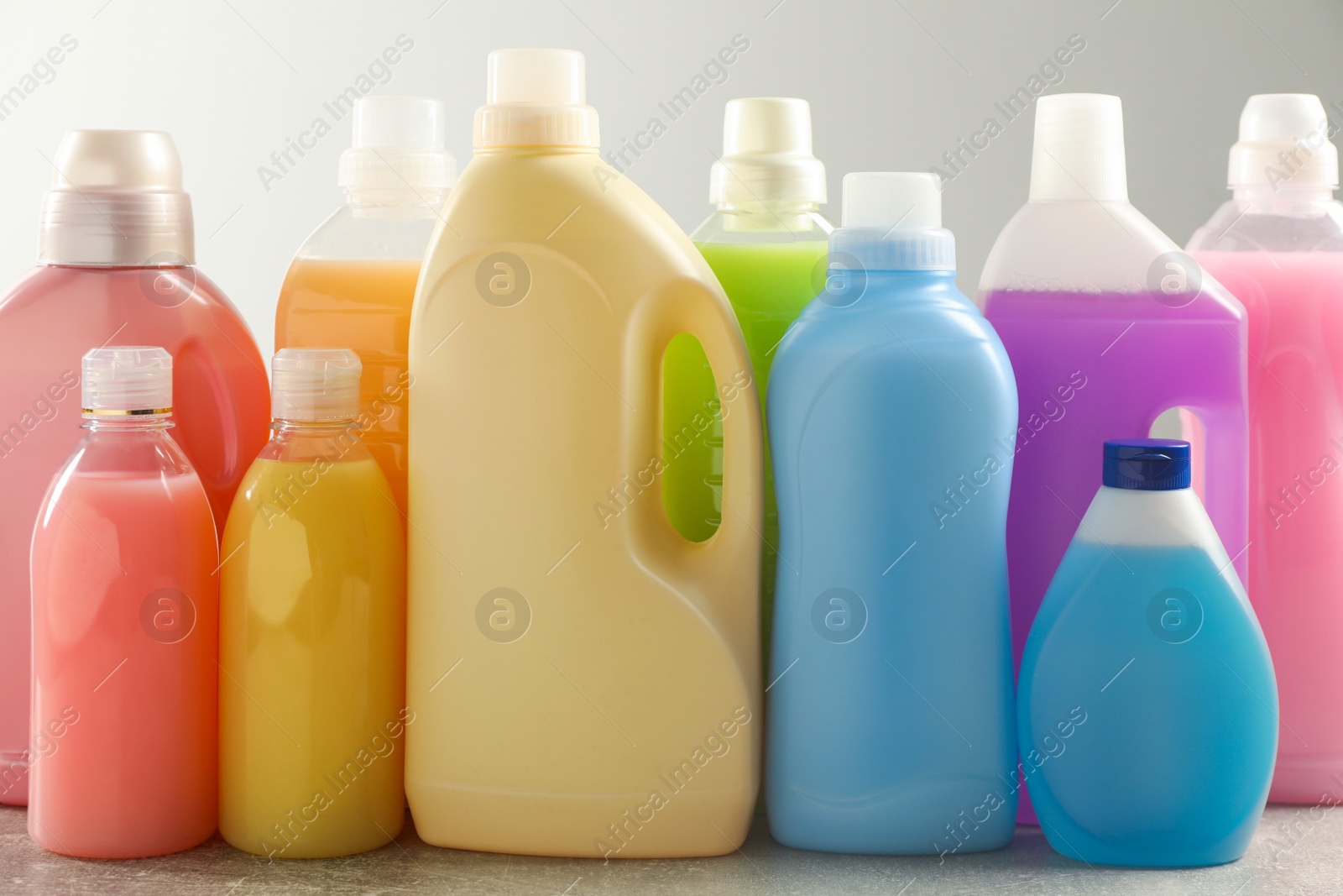 Photo of Different bottles with detergents on grey table