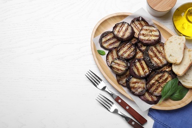 Photo of Delicious grilled eggplant slices served on white wooden table, flat lay. Space for text