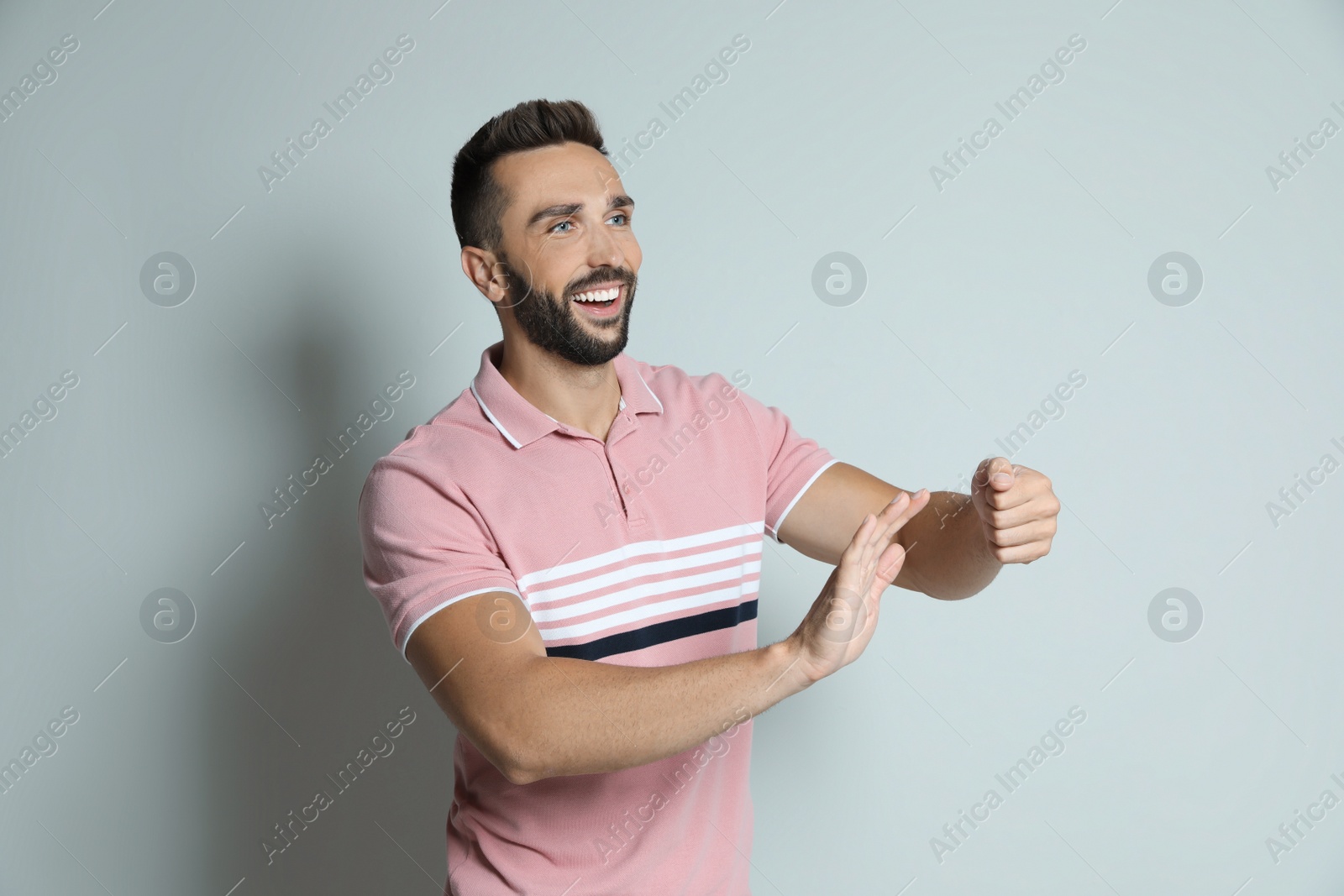 Photo of Happy man pretending to drive car on grey background