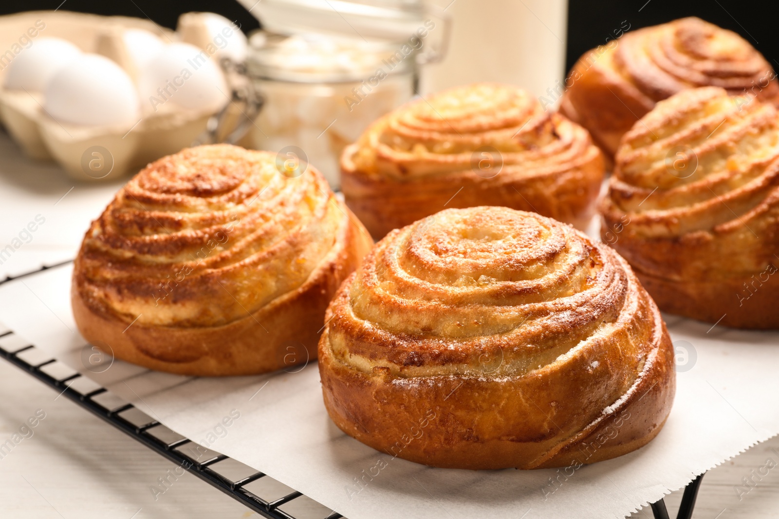 Photo of Cooling rack with tasty buns on table, closeup. Fresh from oven