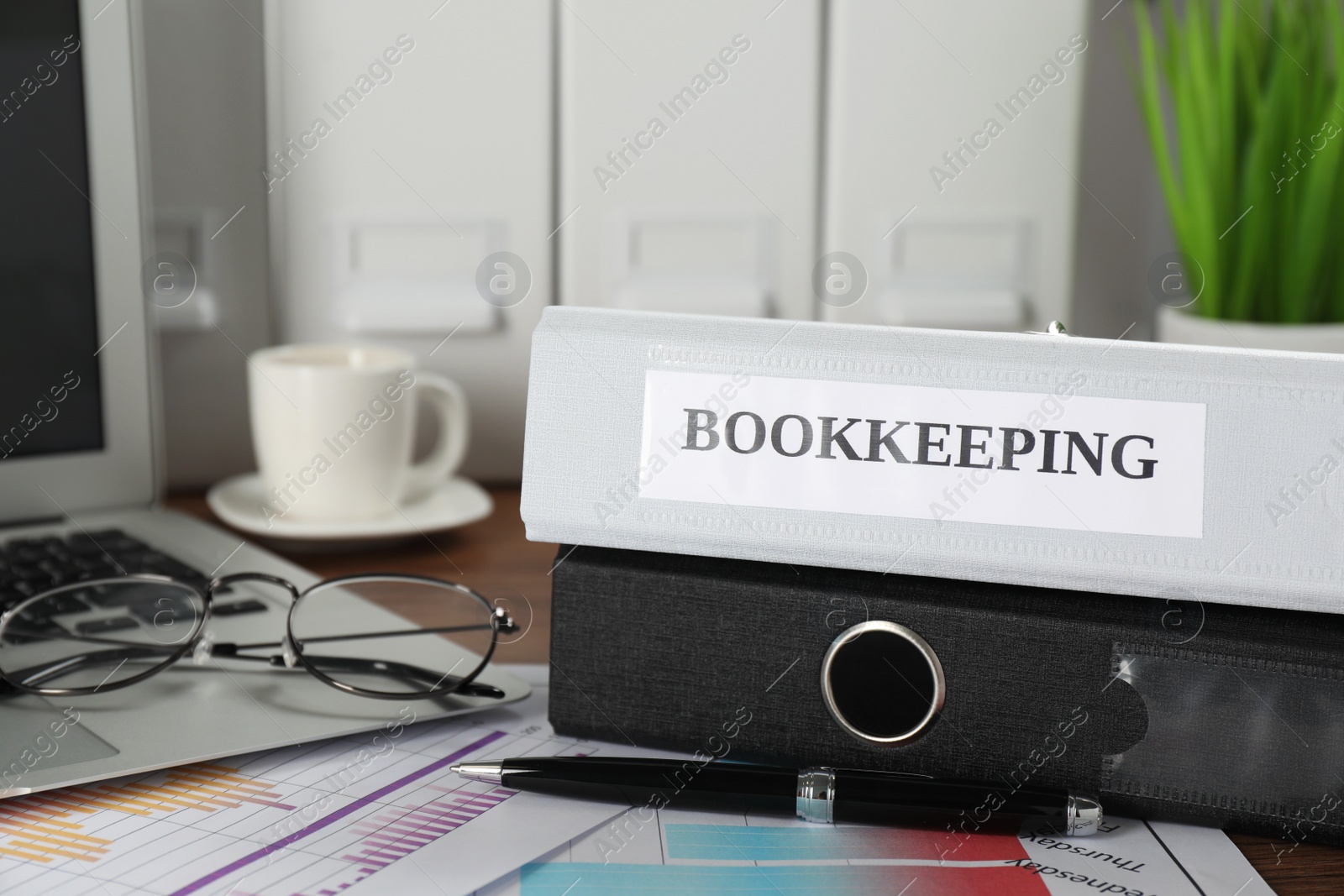 Photo of Folders, laptop and documents on desk in office, closeup. Bookkeeper's workplace