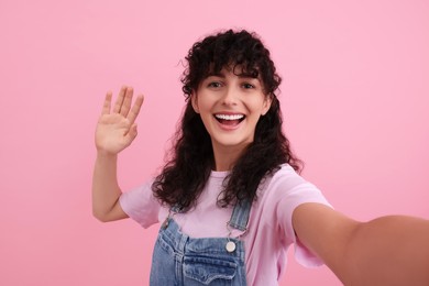 Beautiful woman taking selfie on pink background