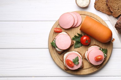 Photo of Delicious sandwiches with boiled sausage, tomato and sauce on white wooden table, flat lay. Space for text