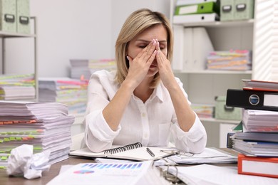 Overwhelmed woman surrounded by documents at workplace in office