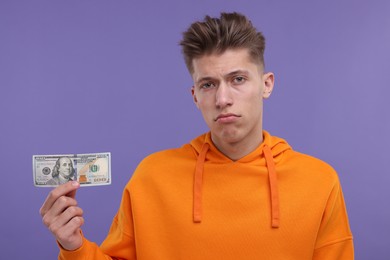 Upset man with dollar banknote on purple background