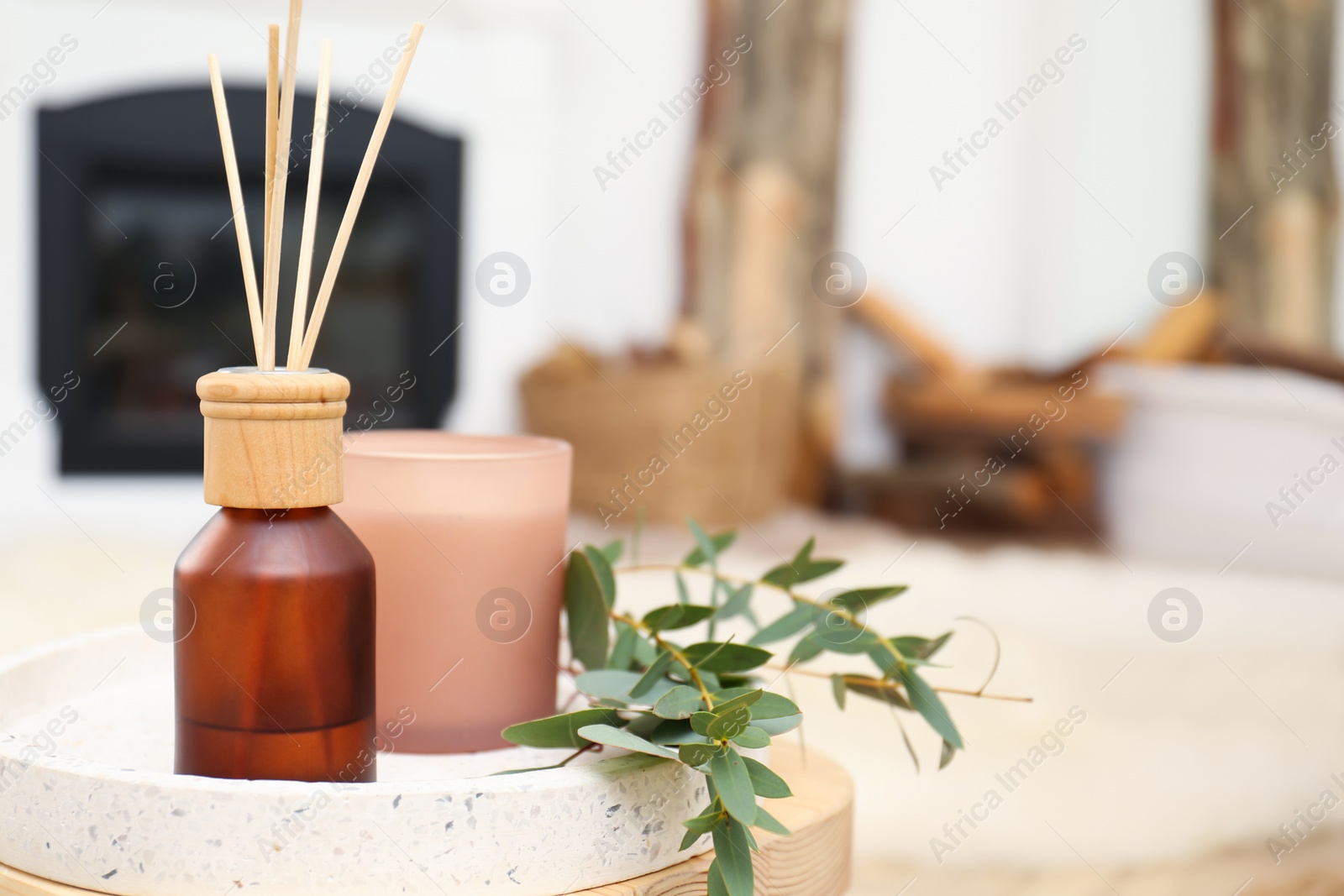 Photo of Reed air freshener with candle and eucalyptus branches on tray indoors, closeup