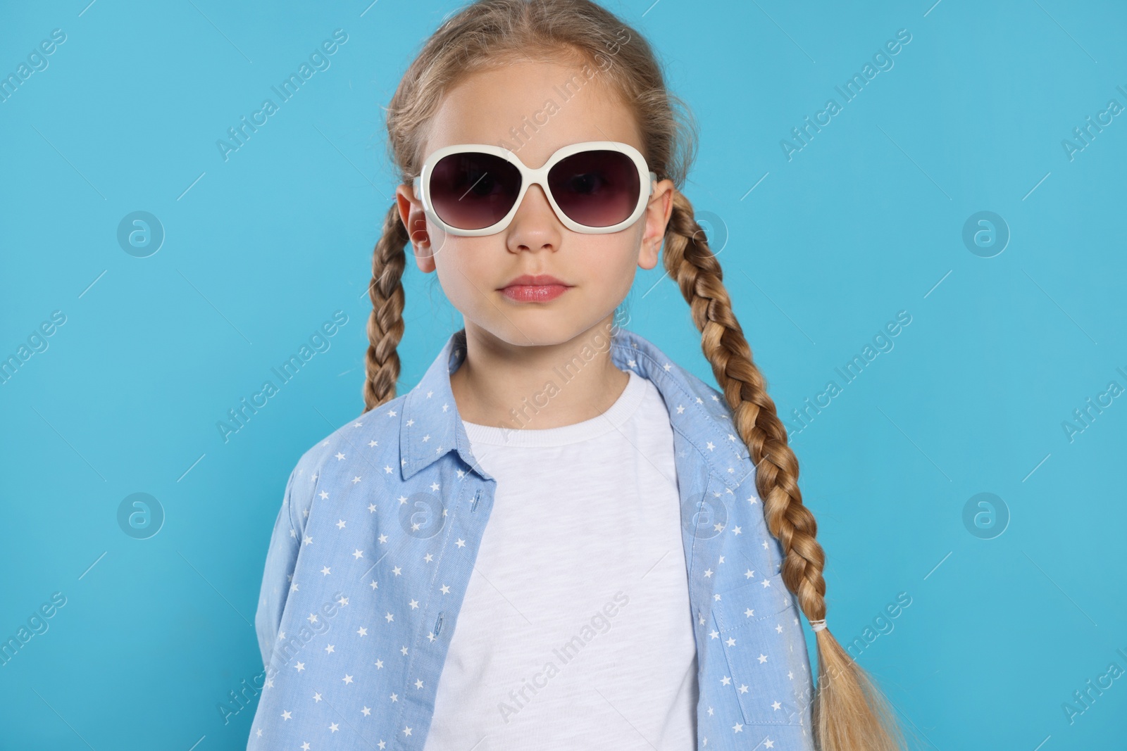 Photo of Girl in stylish sunglasses on light blue background