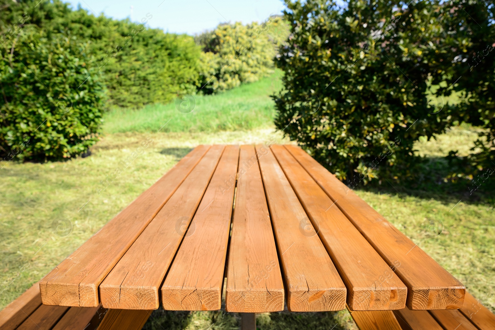 Photo of Empty wooden picnic table with benches in park on sunny day