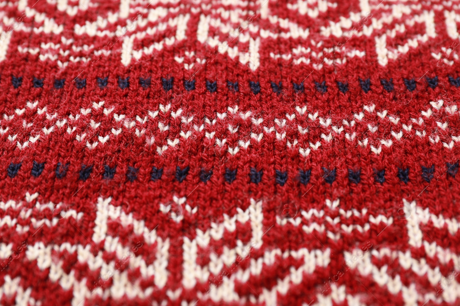 Photo of Warm Christmas sweater with snowflakes as background, closeup