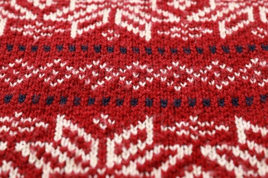 Photo of Warm Christmas sweater with snowflakes as background, closeup