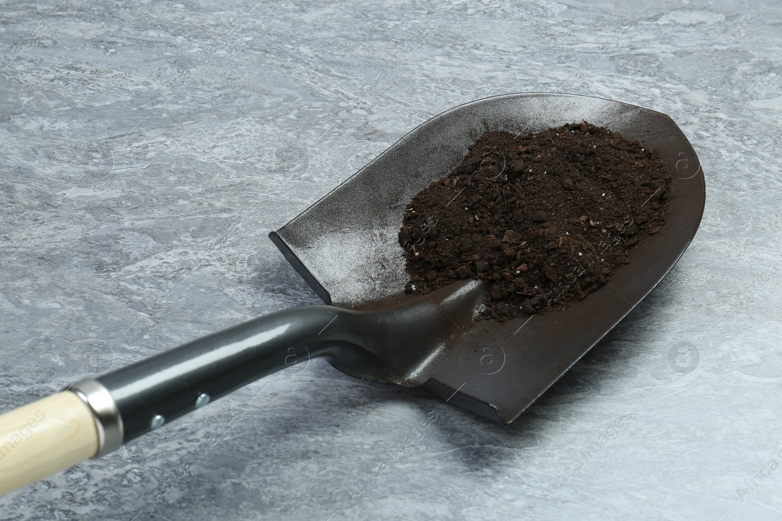 Metal shovel with fertile soil on gray textured surface Photo of Metal shovel with fertile soil on gray textured surface