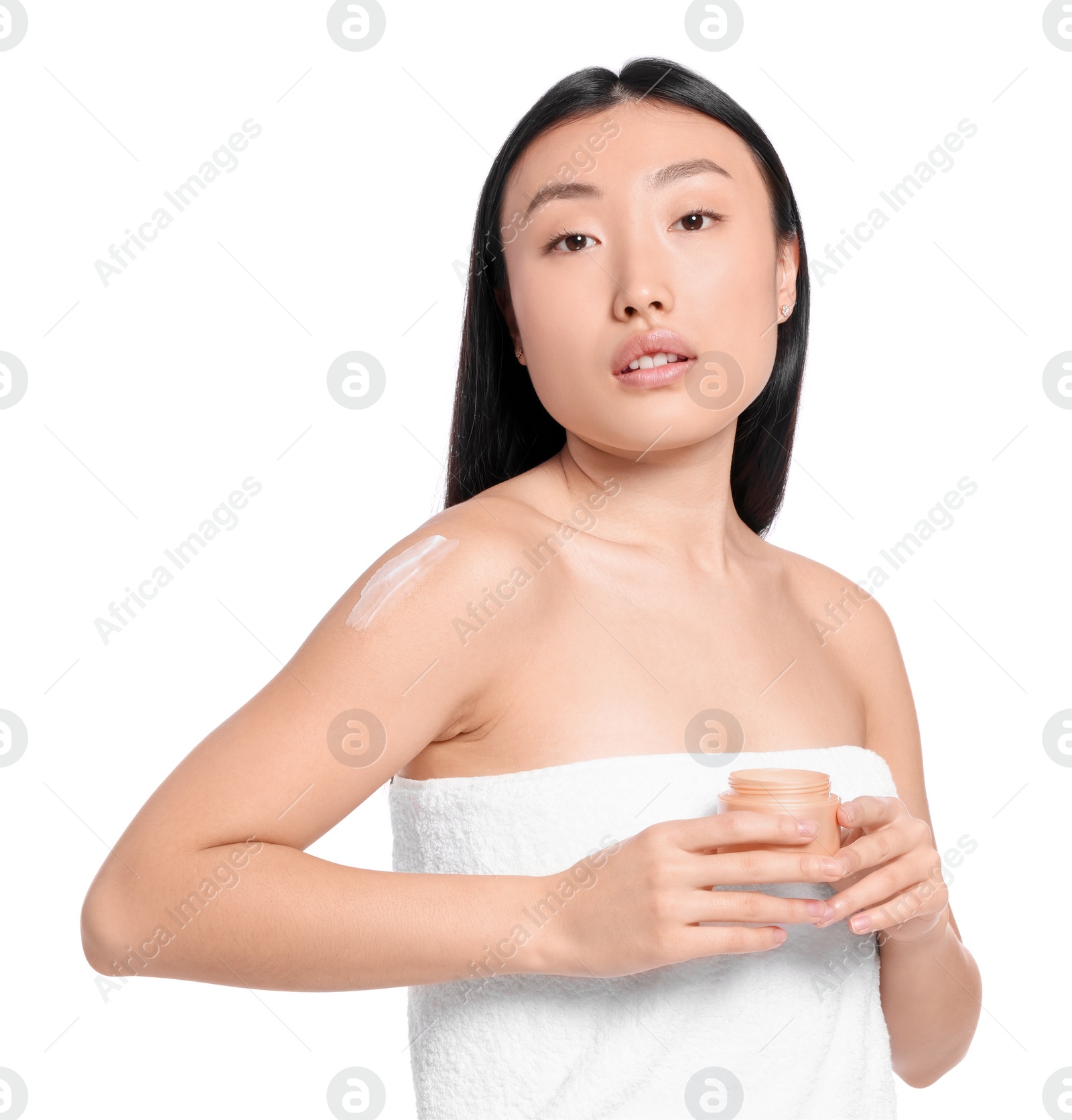 Photo of Beautiful young Asian woman with jar of body cream on white background