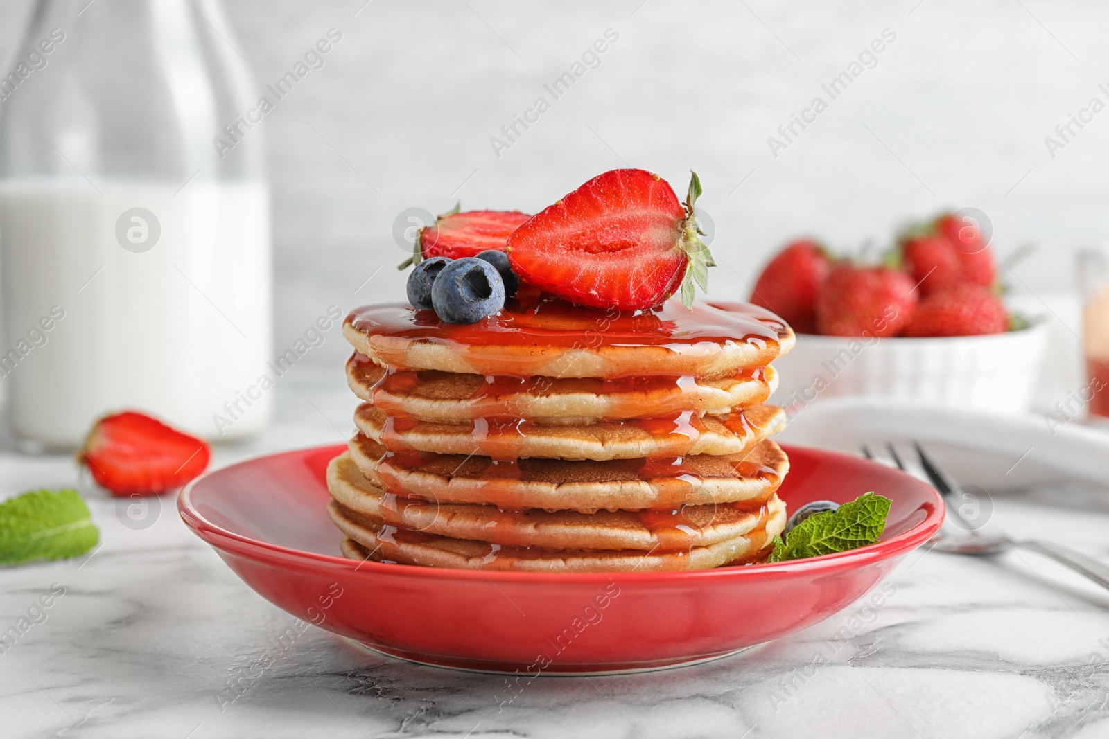 Photo of Plate of delicious pancakes with fresh berries and syrup on white marble table