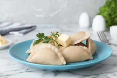 Photo of Plate of tasty dumplings served with parsley and butter on table