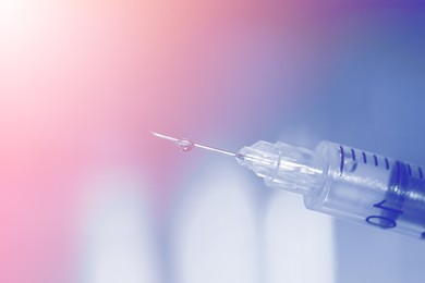 Image of Syringe with medicine against blurred background, closeup. Color toned