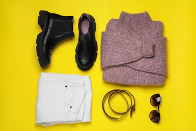 Stylish boots, new clothes and accessories on yellow background, flat lay
