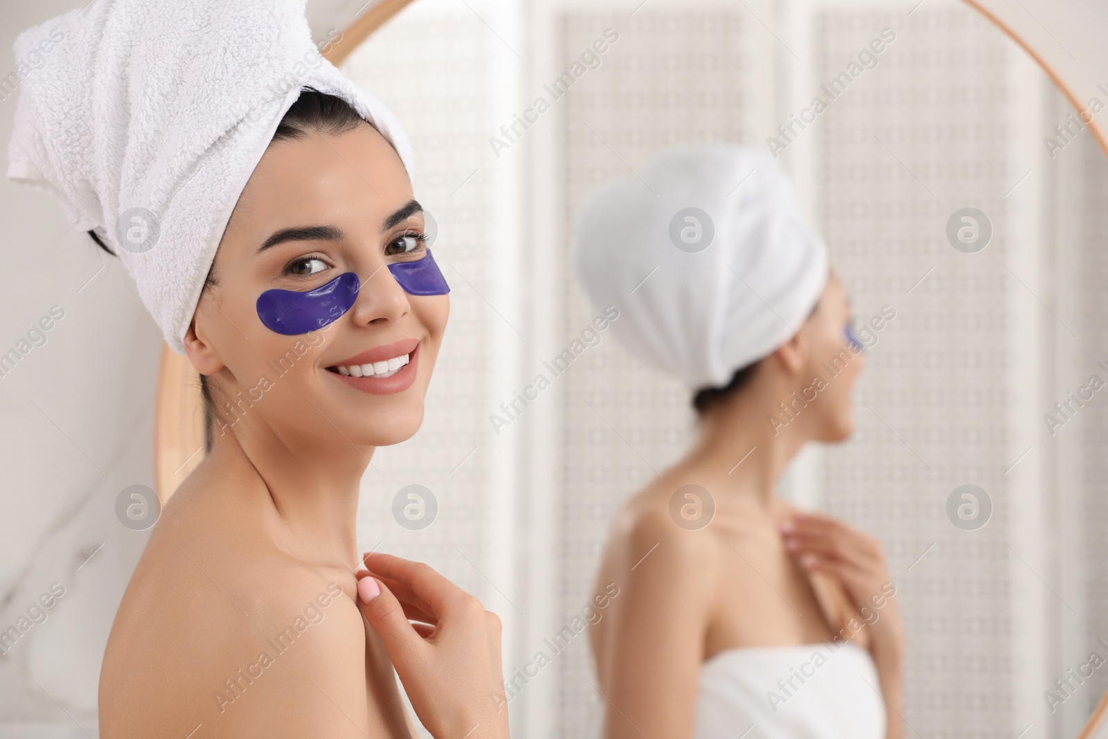 Photo of Beautiful young woman with under eye patches at home, space for text