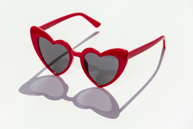Photo of Stylish heart shaped sunglasses on white background