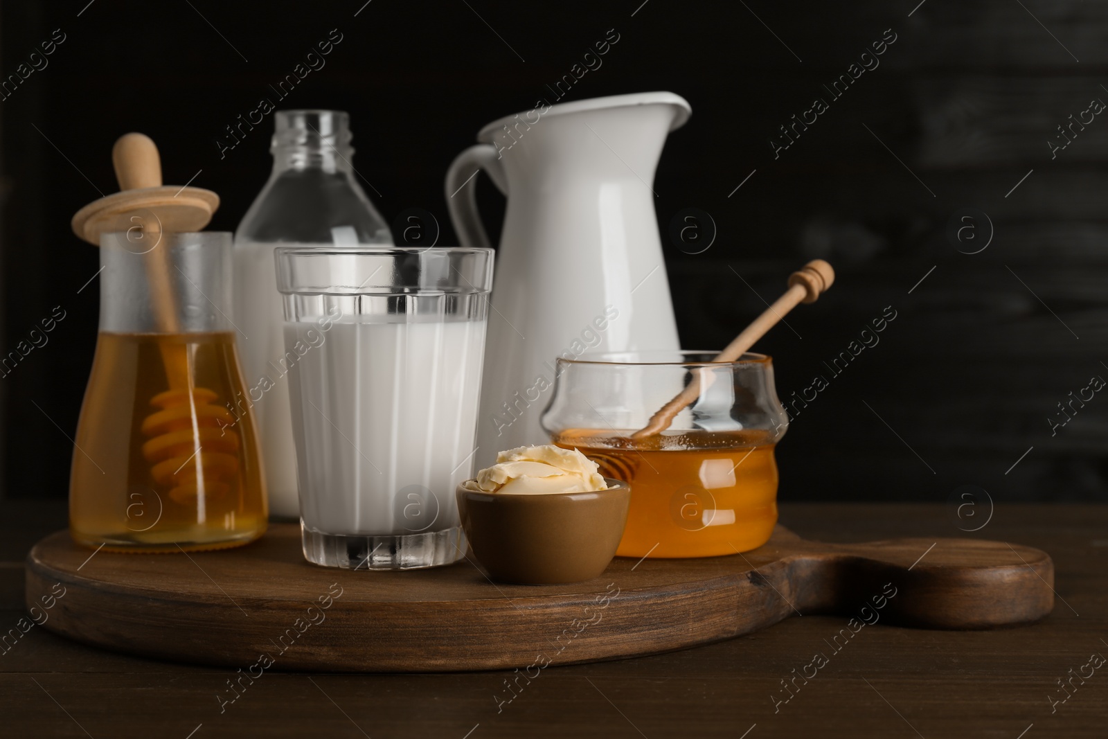 Photo of Jars with tasty honey, milk and butter on wooden table