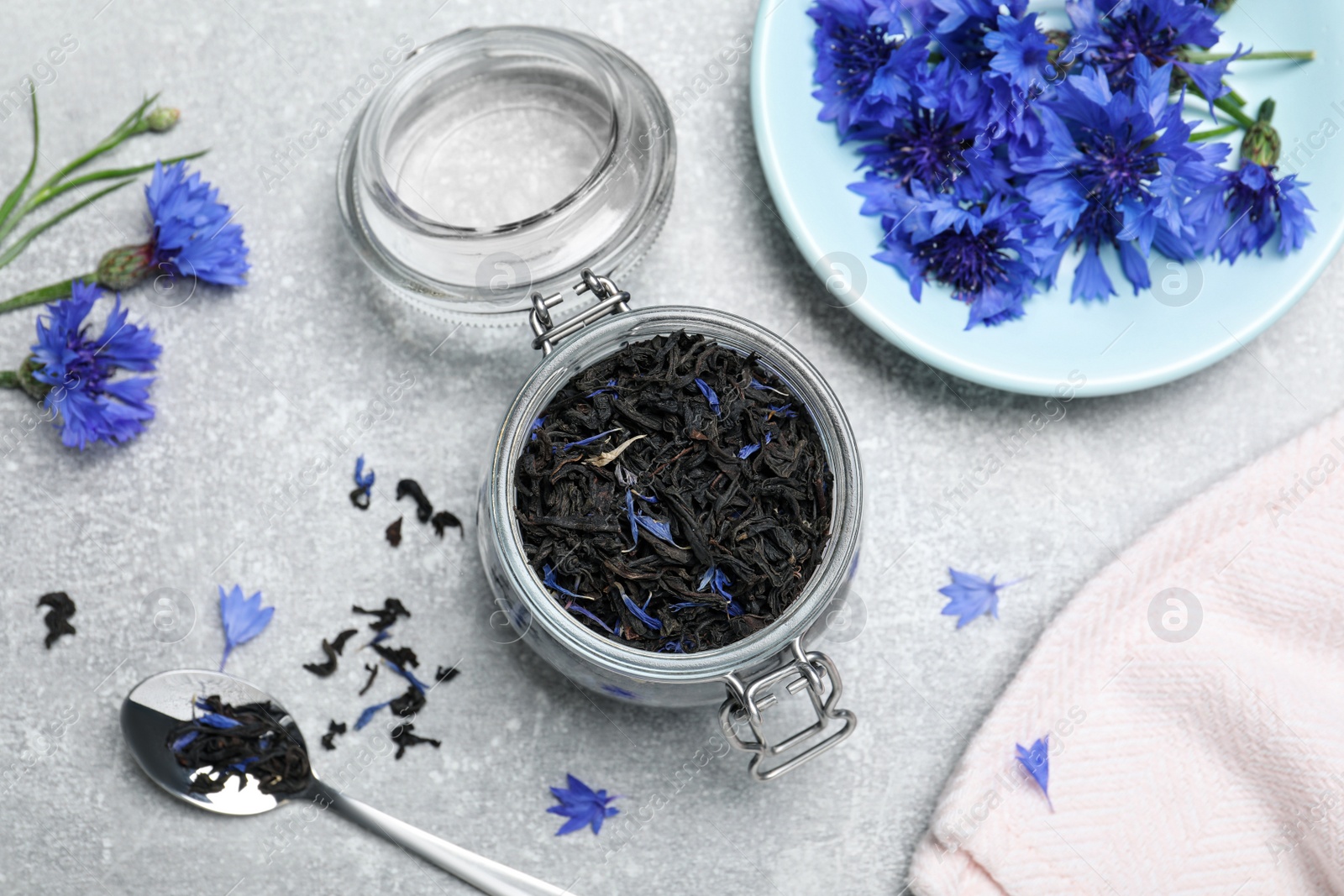 Photo of Flat lay composition with dry tea leaves and cornflowers on light table