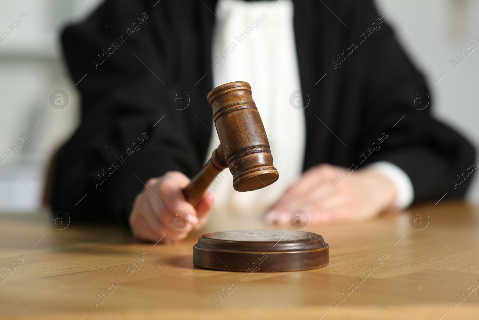 Photo of Judge striking mallet at wooden table in courtroom, closeup