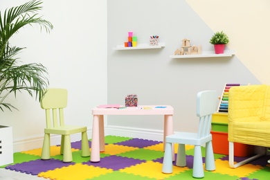 Stylish playroom interior with table, chairs and sofa