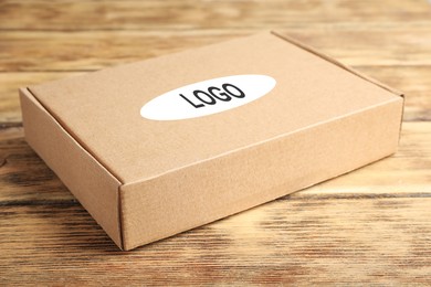 Image of Closed cardboard box with logo on brown wooden table