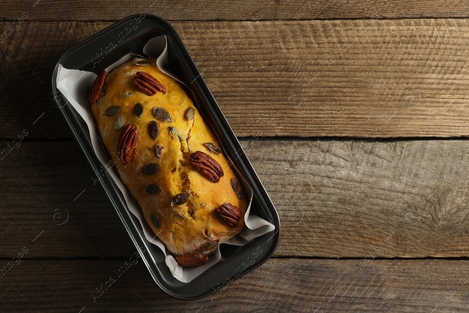 Photo of Delicious pumpkin bread with pecan nuts on wooden table, top view. Space for text