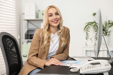 Portrait of happy secretary at table in office