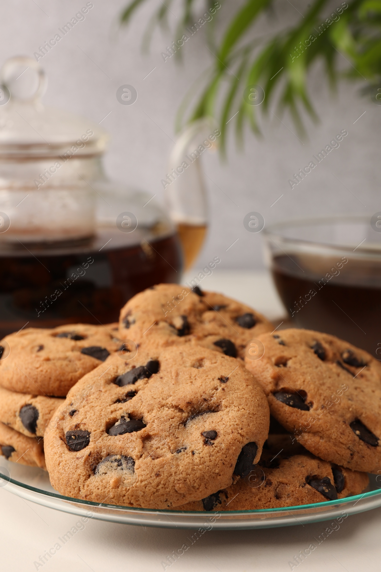 Photo of Delicious chocolate chip cookies and tea on white marble table