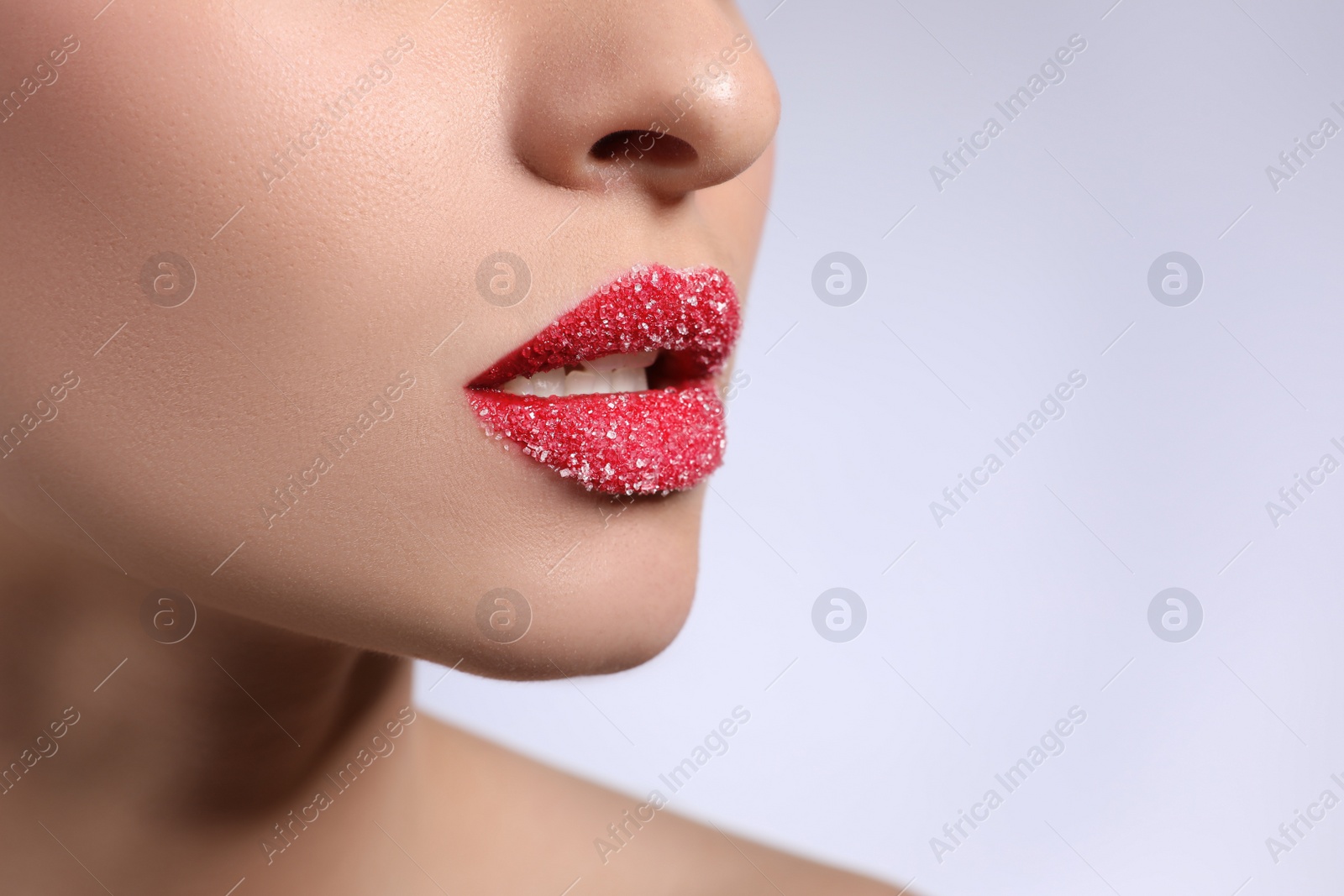 Photo of Young woman with lips covered in sugar on light background, closeup. Space for text