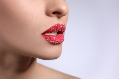 Photo of Young woman with lips covered in sugar on light background, closeup. Space for text