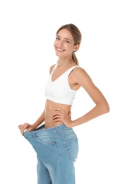 Young slim woman in old big jeans showing her diet results on white background