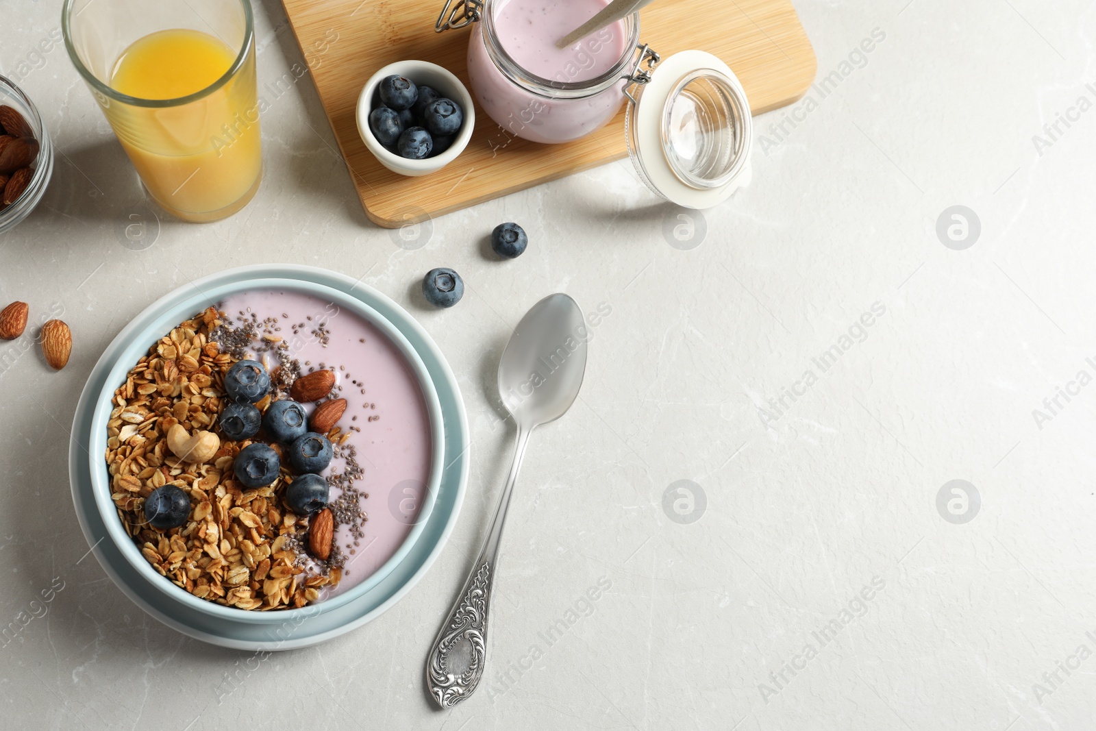 Photo of Bowl of tasty oatmeal with blueberries and yogurt on light grey marble table, flat lay. Space for text